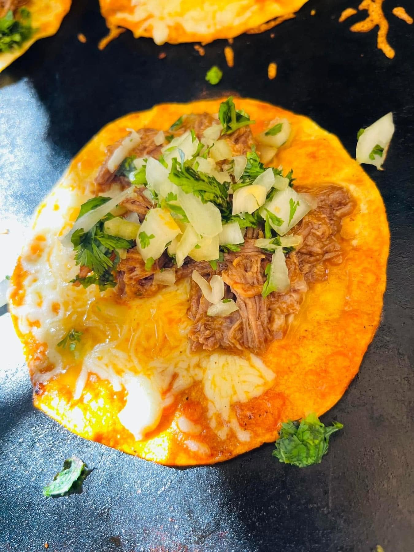 Taco de birria con queso, cebolla y cilantro